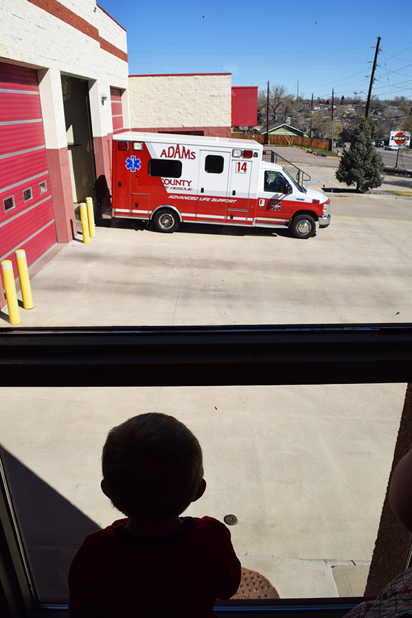 Ambulance leaving fire station while child watches